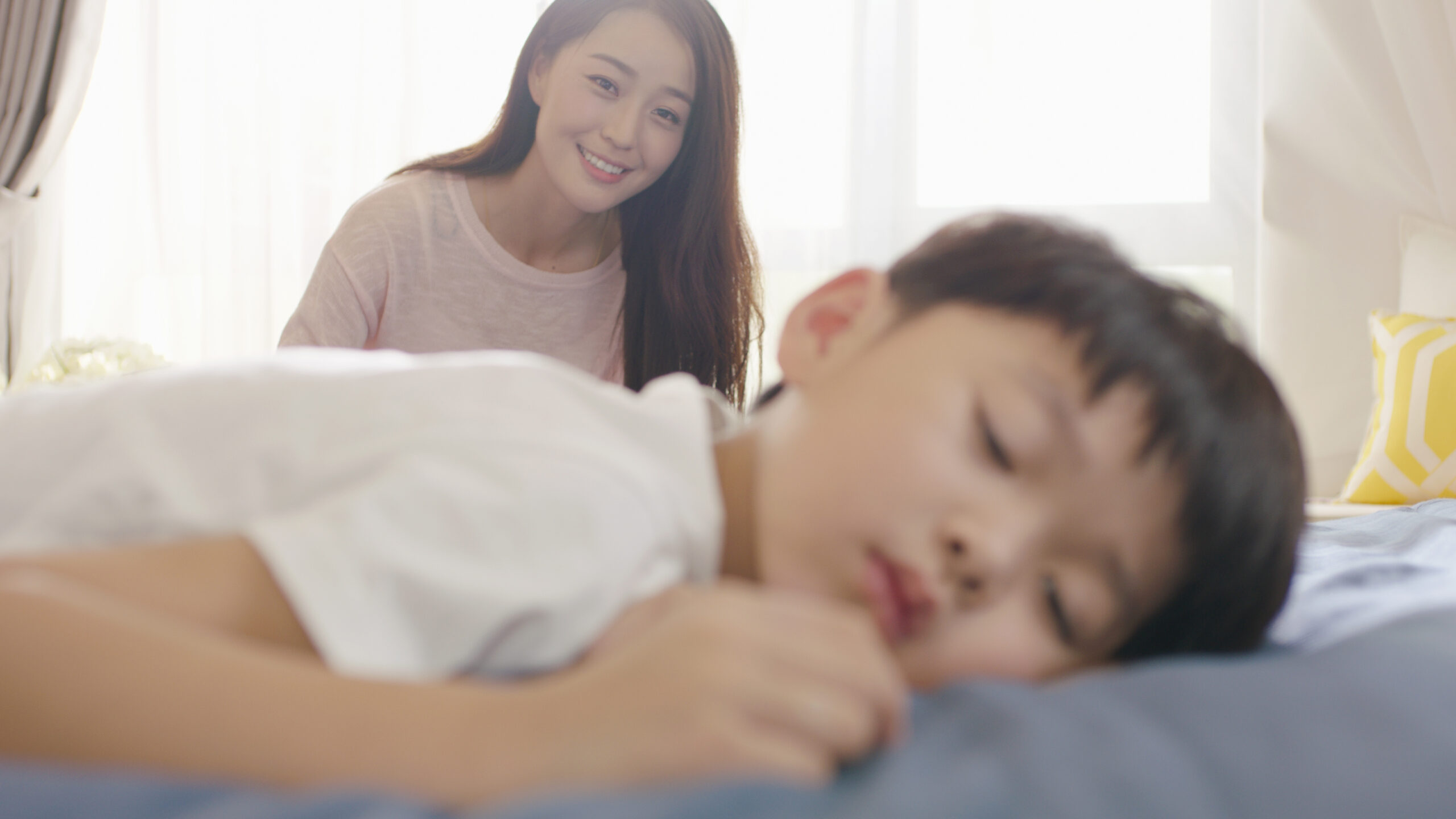 Smiling,Asian,Mother,Looking,At,His,Son,In,Sleep,In